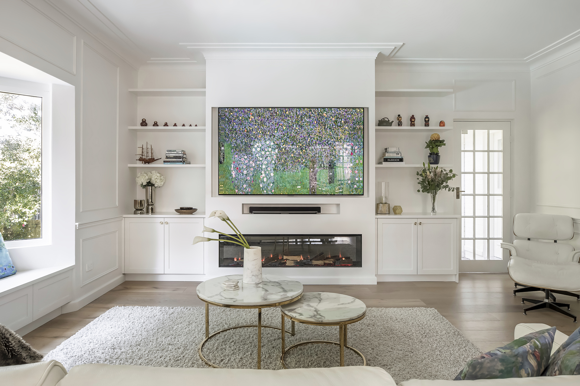 A sophisticated living room renovation by HoverCo, featuring custom built-in shelving, a modern fireplace, elegant white cabinetry, and a stylish marble coffee table for a timeless design.