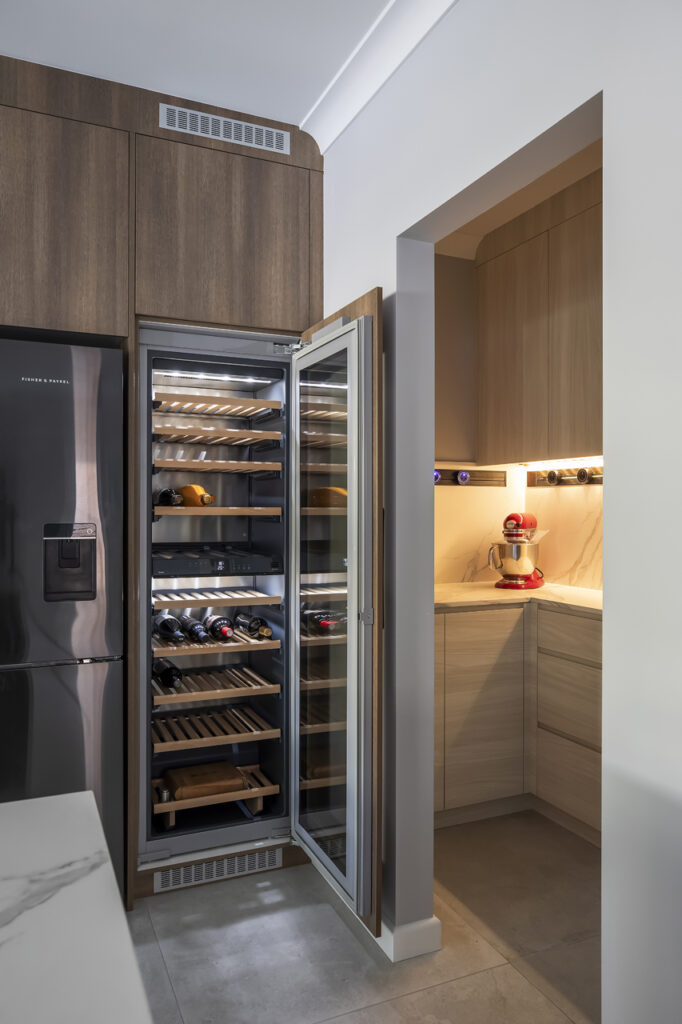 A luxury wine cellar in Frenchs Forest created by Hoverco, featuring built-in wooden racks, LED lighting, and a sleek black fridge.