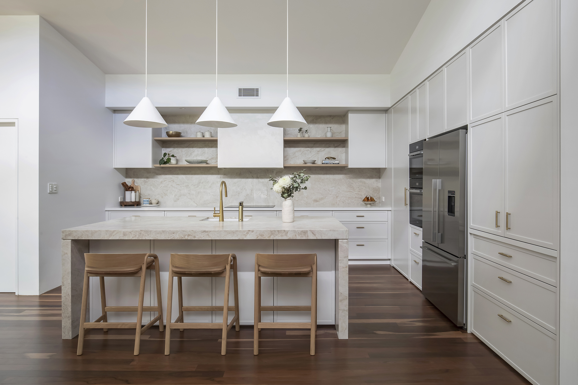 A stunning modern kitchen renovation by HoverCo, featuring a marble island, sleek white cabinetry, gold fixtures, and contemporary pendant lighting for a luxurious finish.