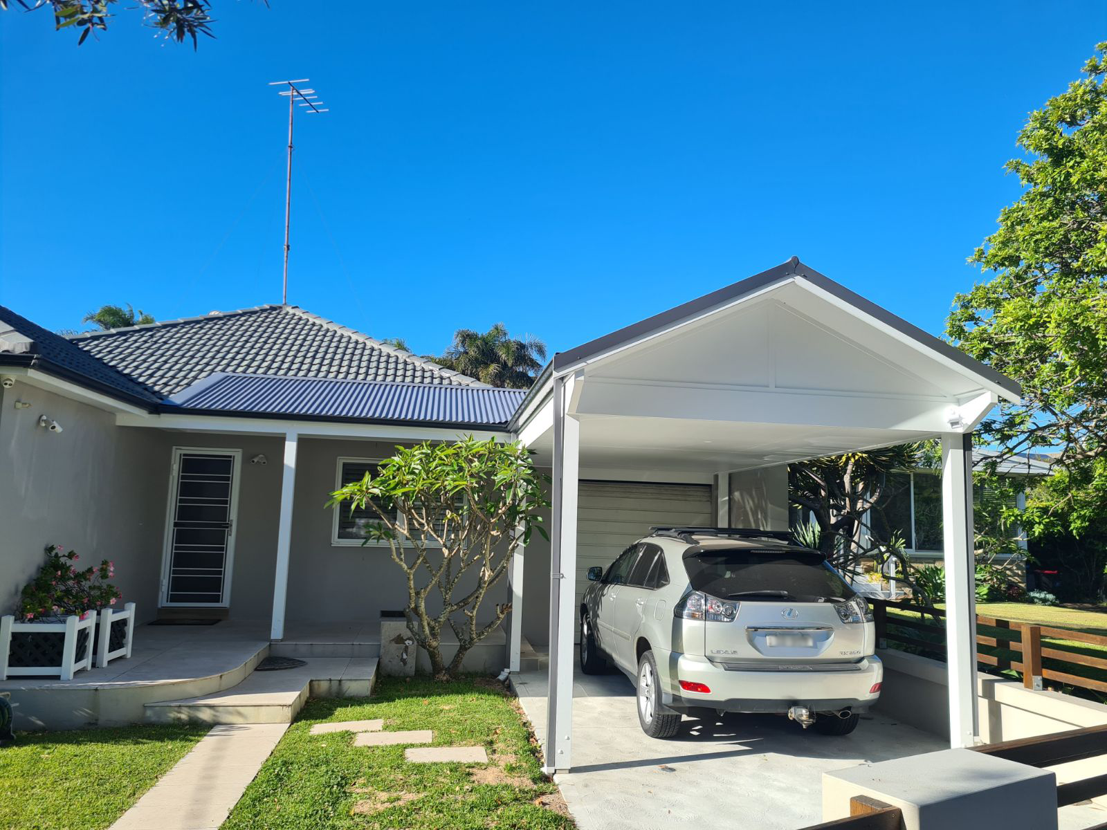 A custom-built steel carport installation by HoverCo, providing durable and stylish protection for vehicles in a modern residential setting.
